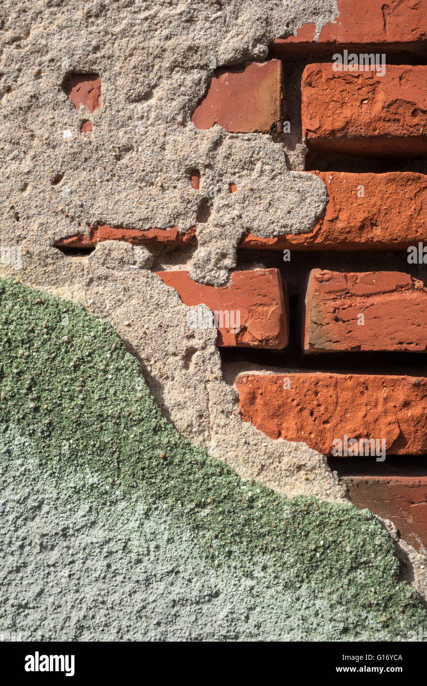 Crumbled gray green plaster on a brick wall Stock Photo