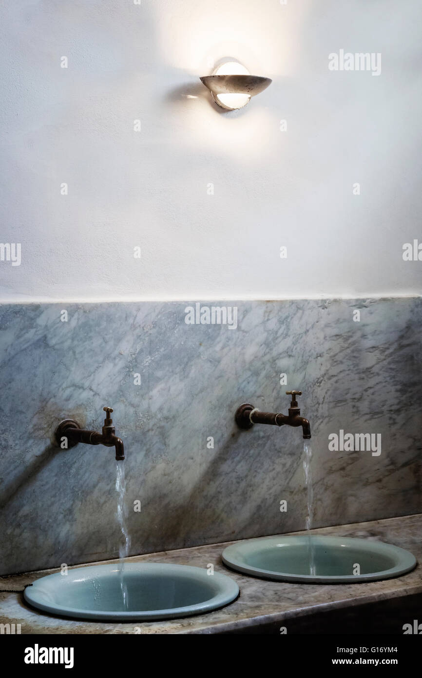two vintage washbasins with running water taps Stock Photo