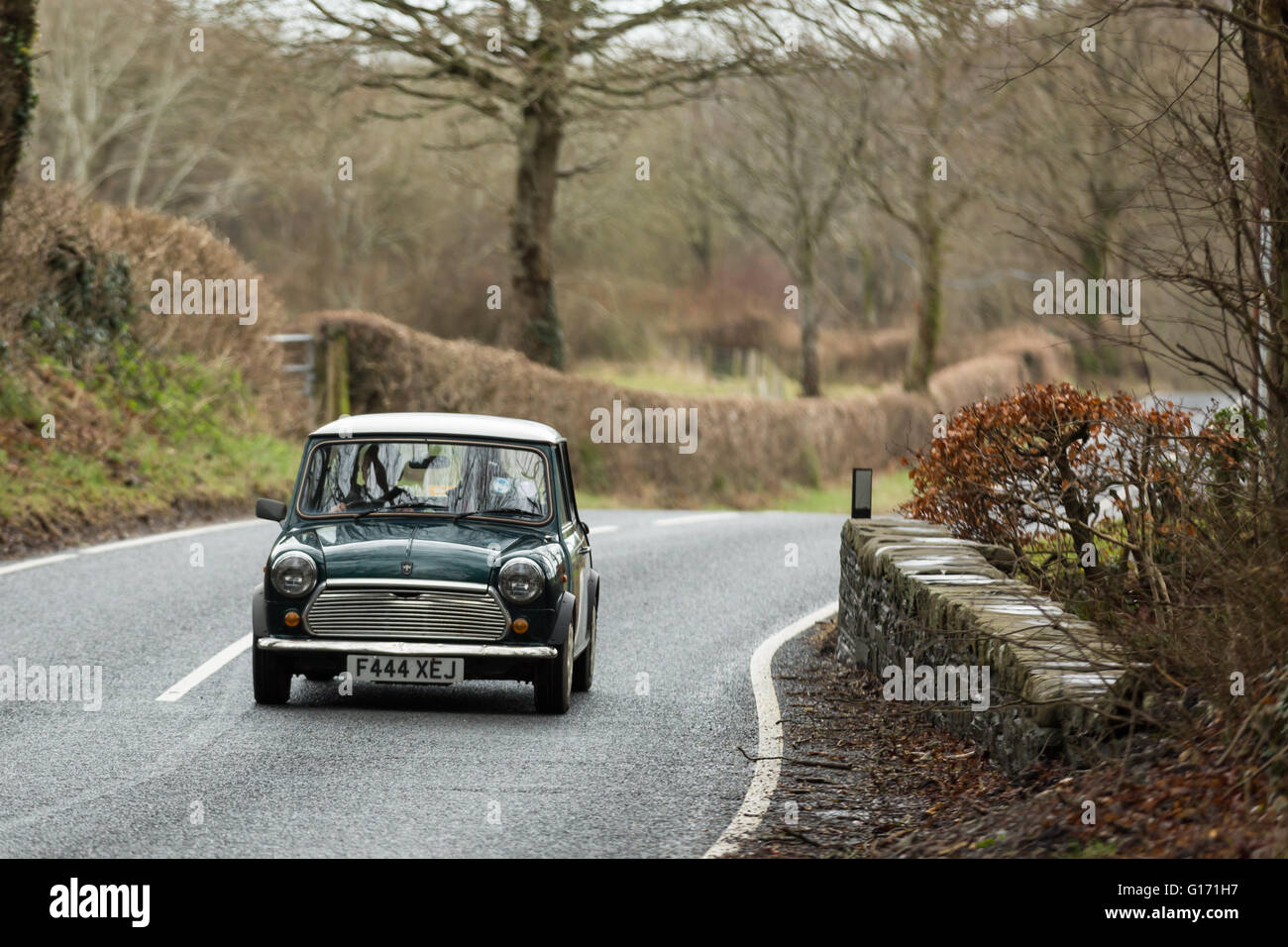 A green vintage mini driving along a road Stock Photo