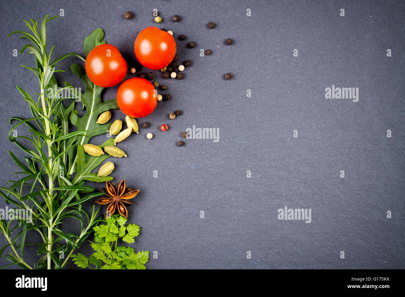 Fresh green herbs and spices against black slate background Stock Photo