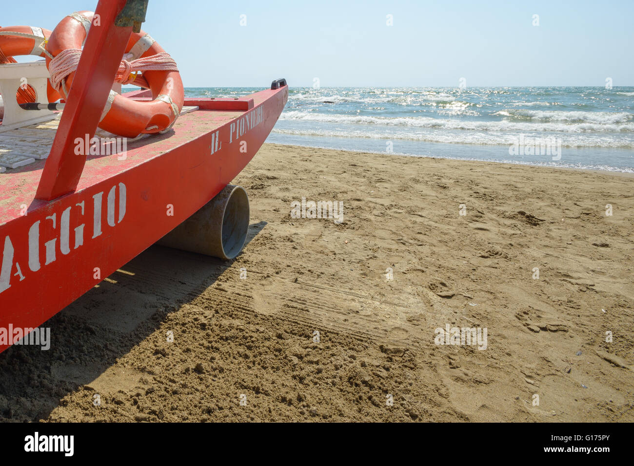 Red rescue boats on an italian beach, a blue sky in background. On the boat there is words meaning safeguard in italian Stock Photo