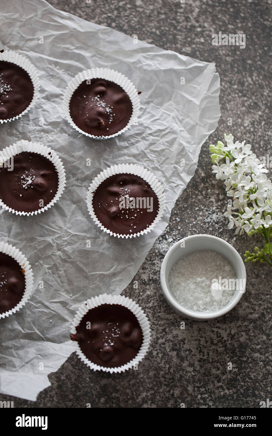 Chocolate cups filled with date caramel with sea salt on a white paper and grey background Stock Photo