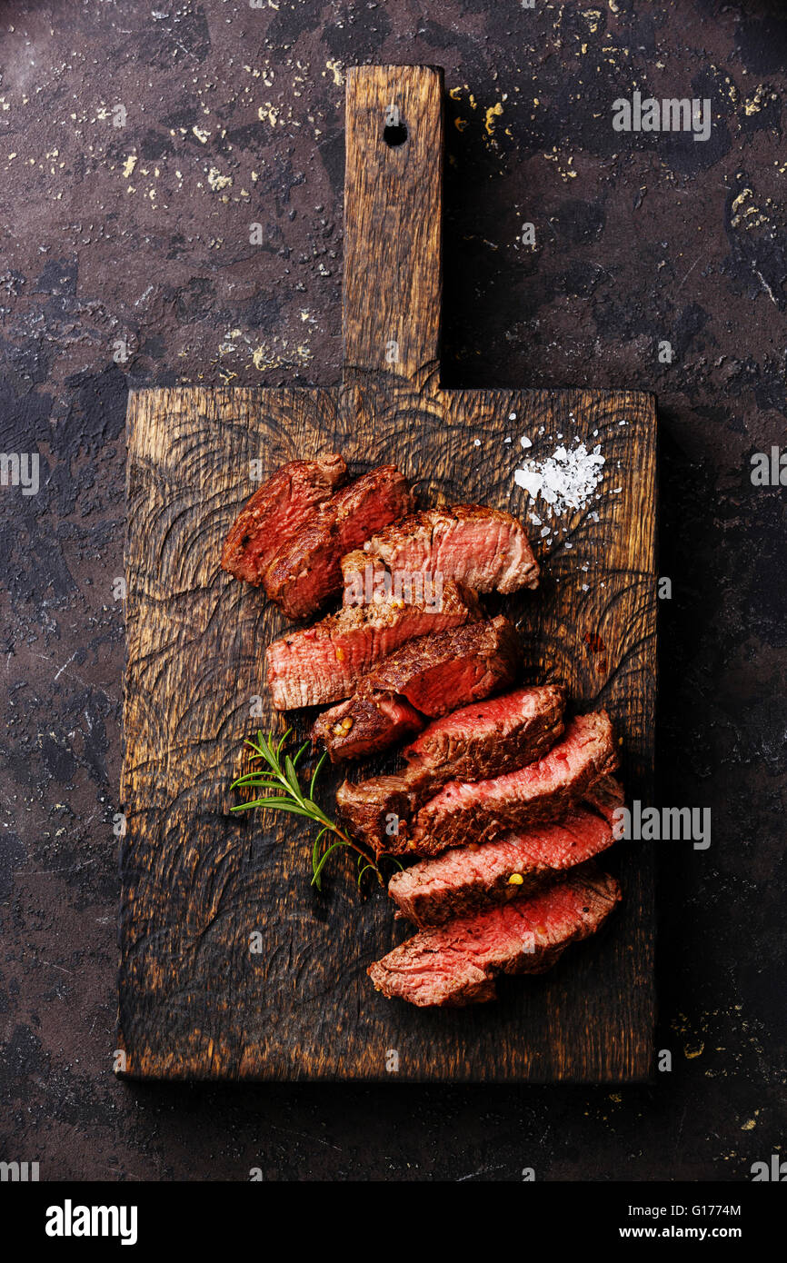 Sliced grilled steak roastbeef and rosemary on wooden cutting board background Stock Photo