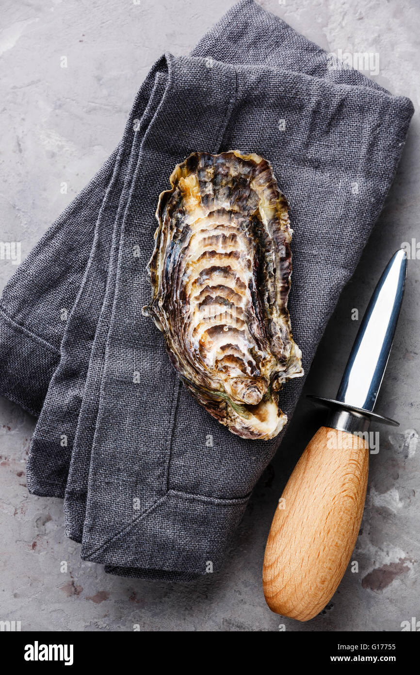 Open Oyster and oyster knife on gray napkin background Stock Photo
