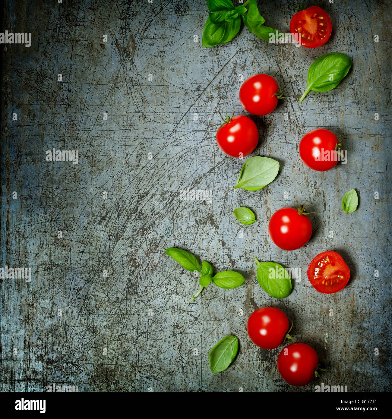 Cherry tomatoes with basil leaves on rustic background Stock Photo - Alamy