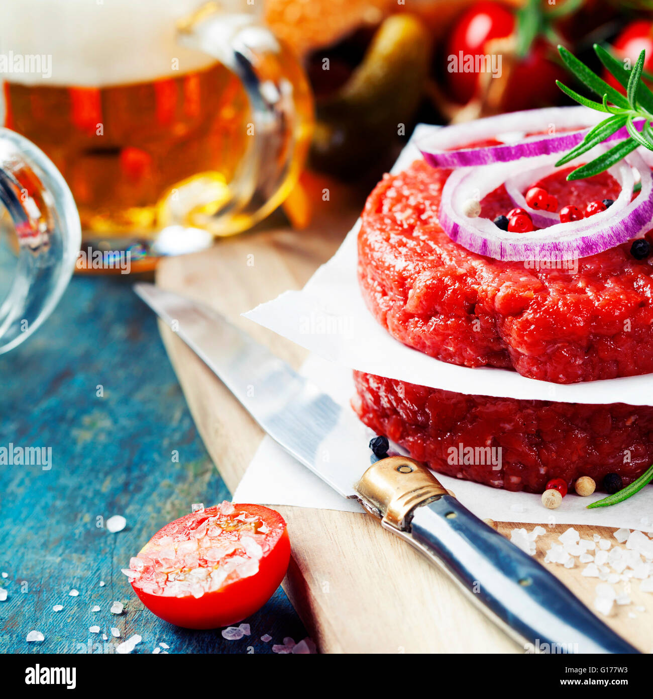 Raw Ground beef meat Burger steak cutlets with seasoning,vegetables and beer on vintage wooden boards Stock Photo