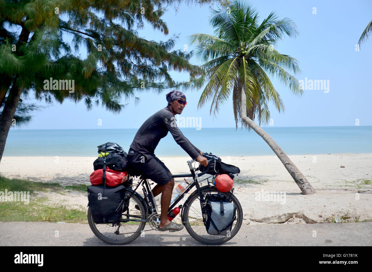 Thai man riding bicycle on road near Thung Wua Laen Beach on September 21, 2015 in Chumphon, Thailand Stock Photo