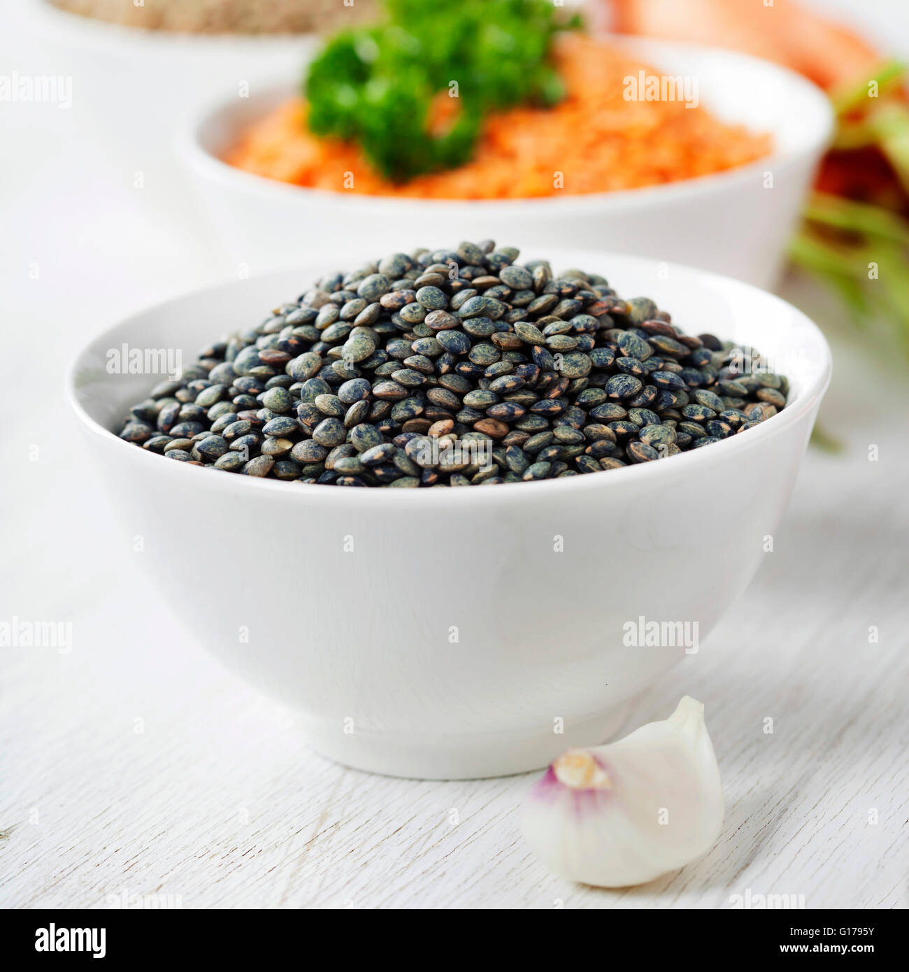 Bowls of assorted dried lentils with vegetables over white Stock Photo