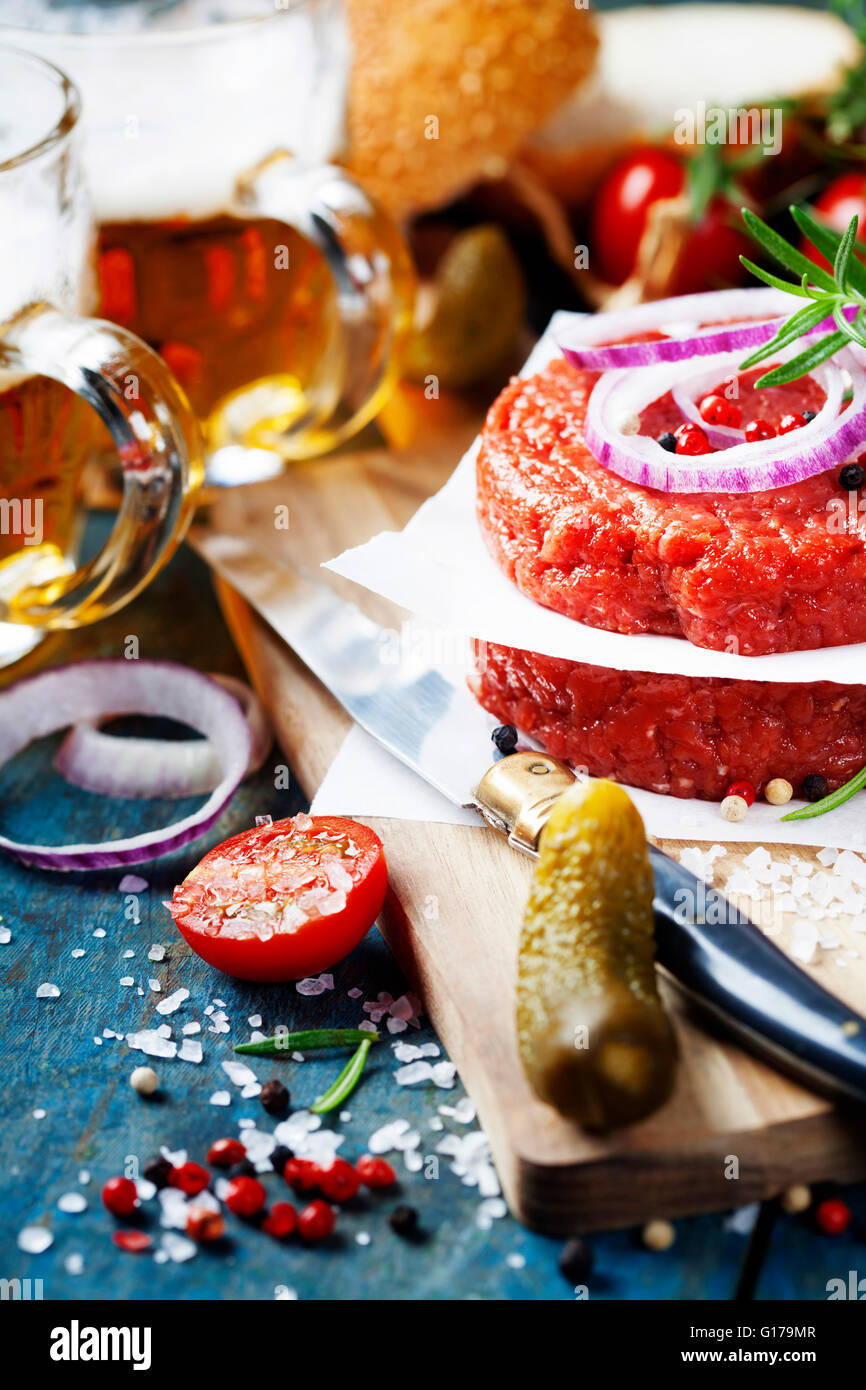 Raw Ground beef meat Burger steak cutlets with seasoning,vegetables and beer on vintage wooden boards Stock Photo