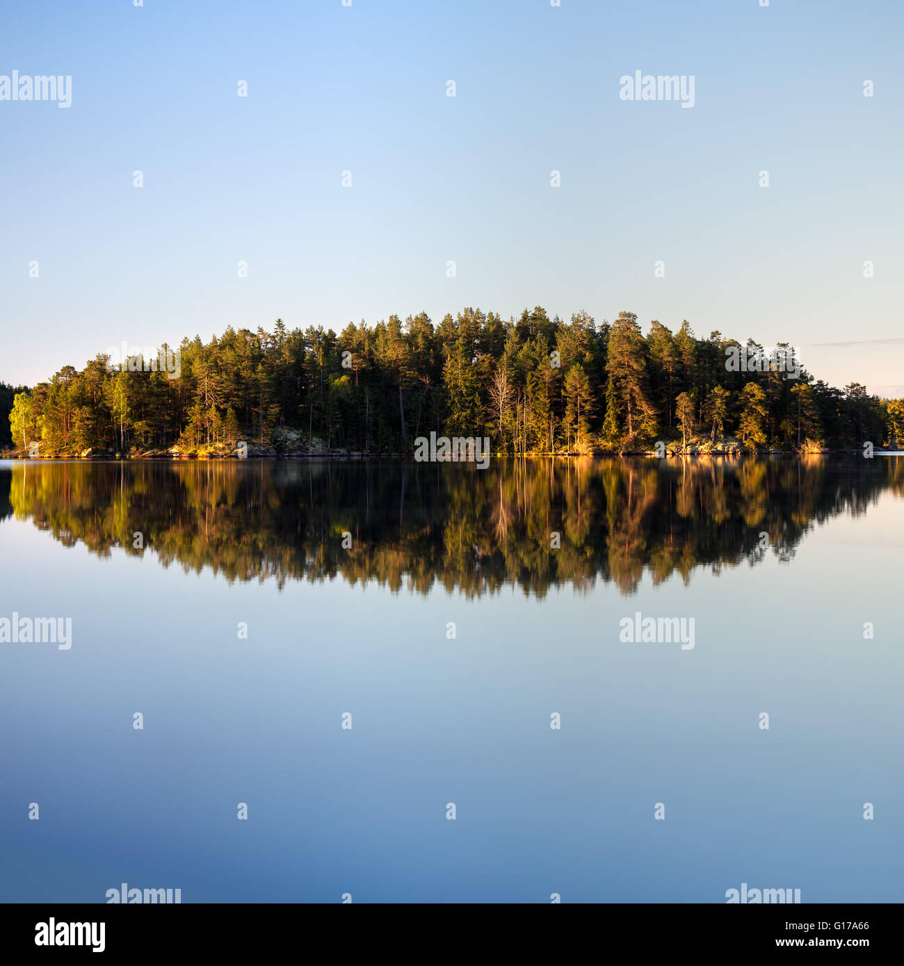 Swedish landscape by lake with perfect reflections of trees and cliffs Stock Photo