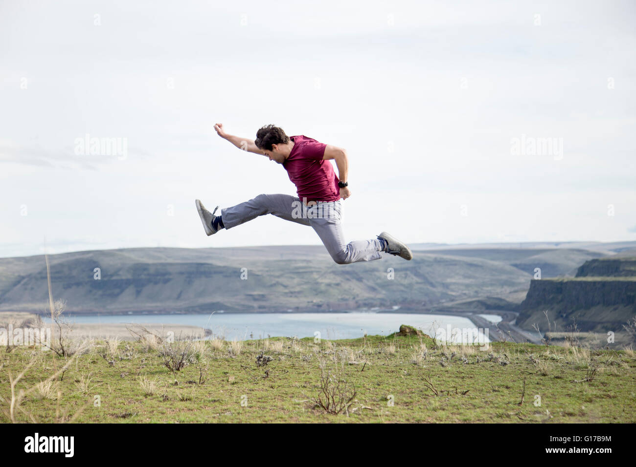 Man jumping, in mid air, on mountain top, Colombia River Gorge, Washington, USA Stock Photo