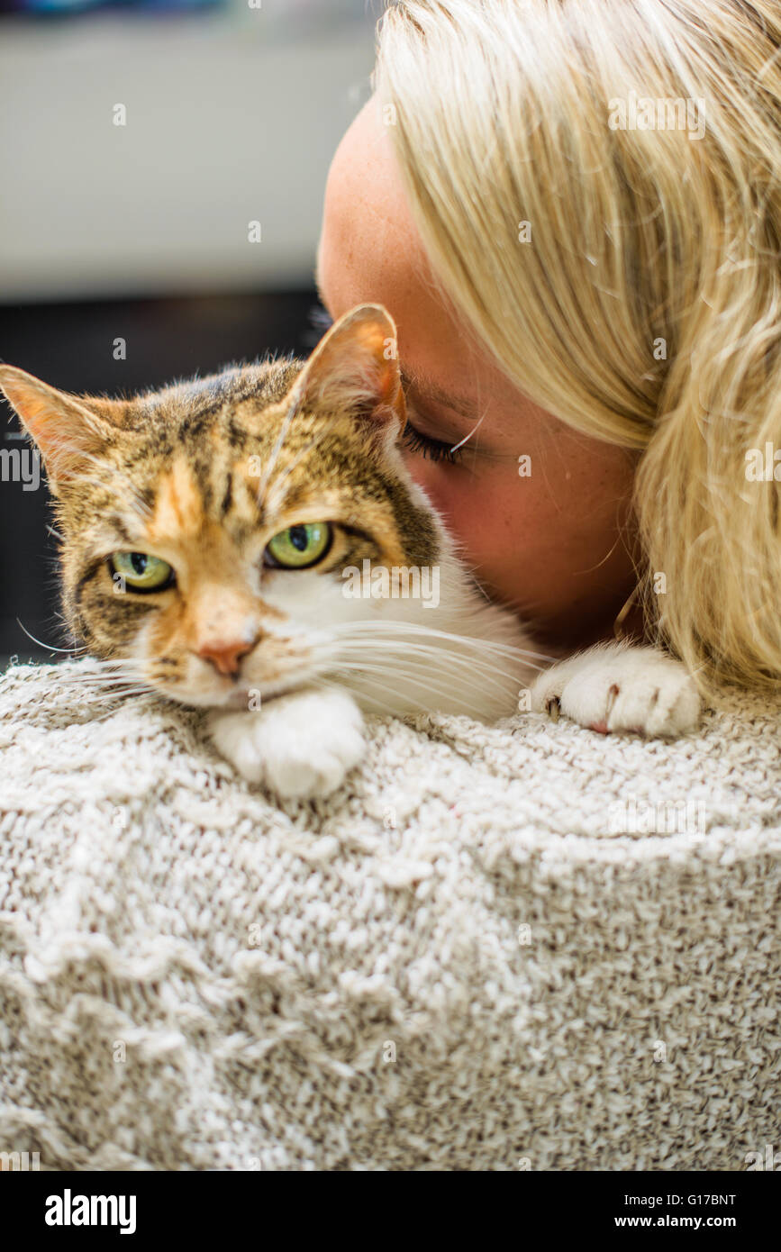 Over the shoulder of woman nuzzling cat Stock Photo