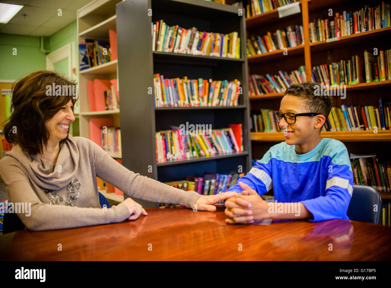 Guidance counselor and teenage boy in school library smiling Stock Photo