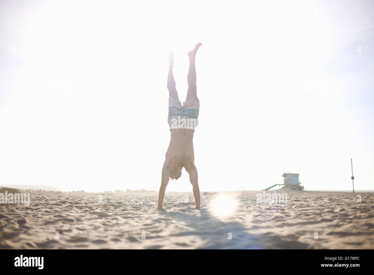 Mid adult man doing handstand on beach Stock Photo