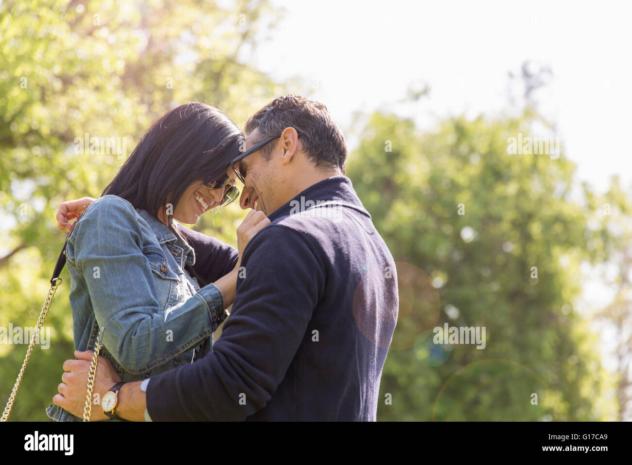 Couple in park face to face hugging and smiling Stock Photo
