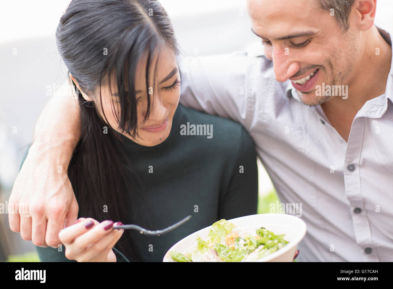 Couple sharing lunch looking down smiling Stock Photo