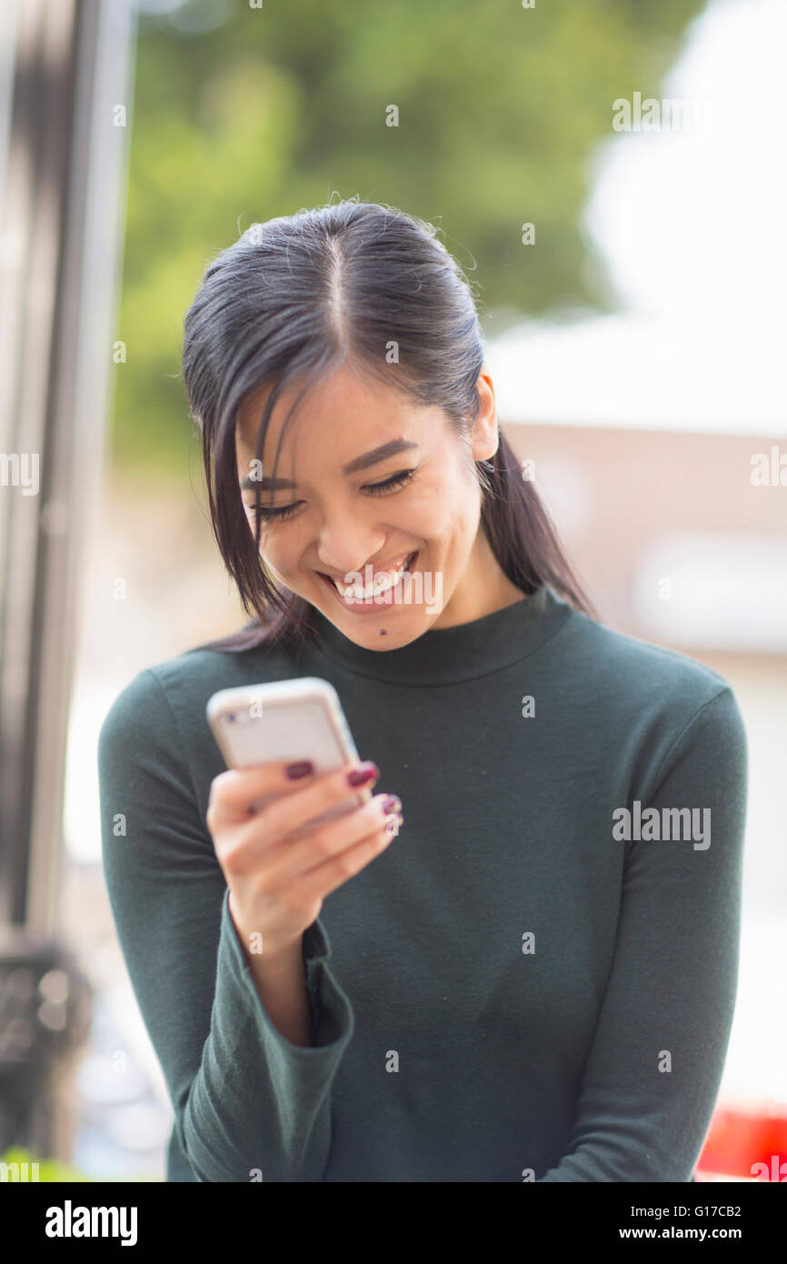 Woman holding smartphone looking down smiling Stock Photo