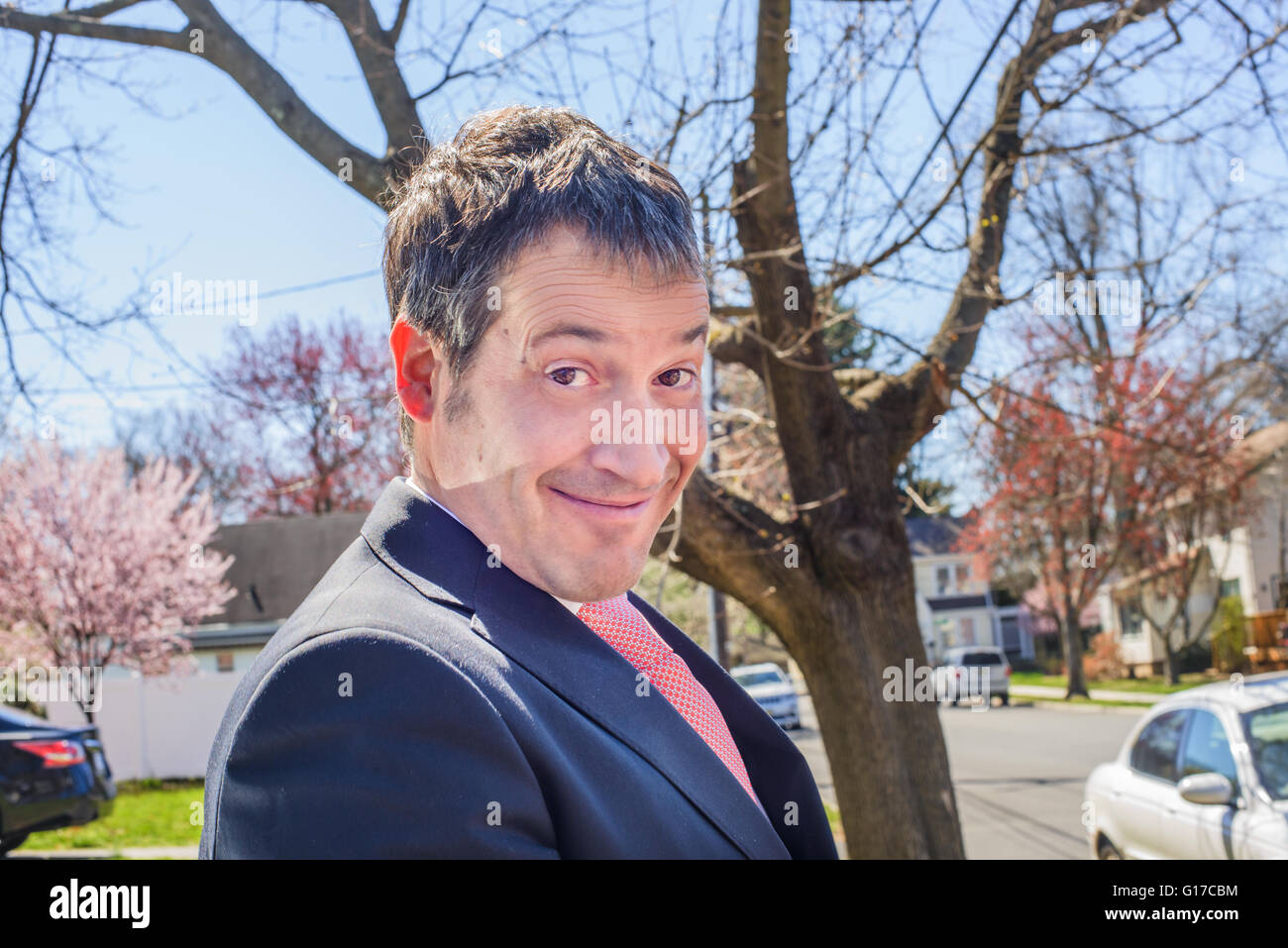 Portrait of business man in residential area pulling face at camera smiling Stock Photo