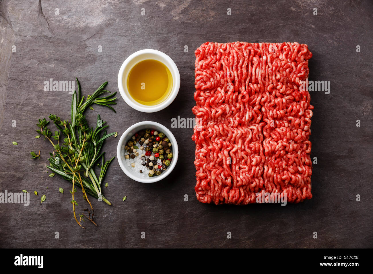 Minced meat on stone slate background with pepper, oil and herbs Stock Photo