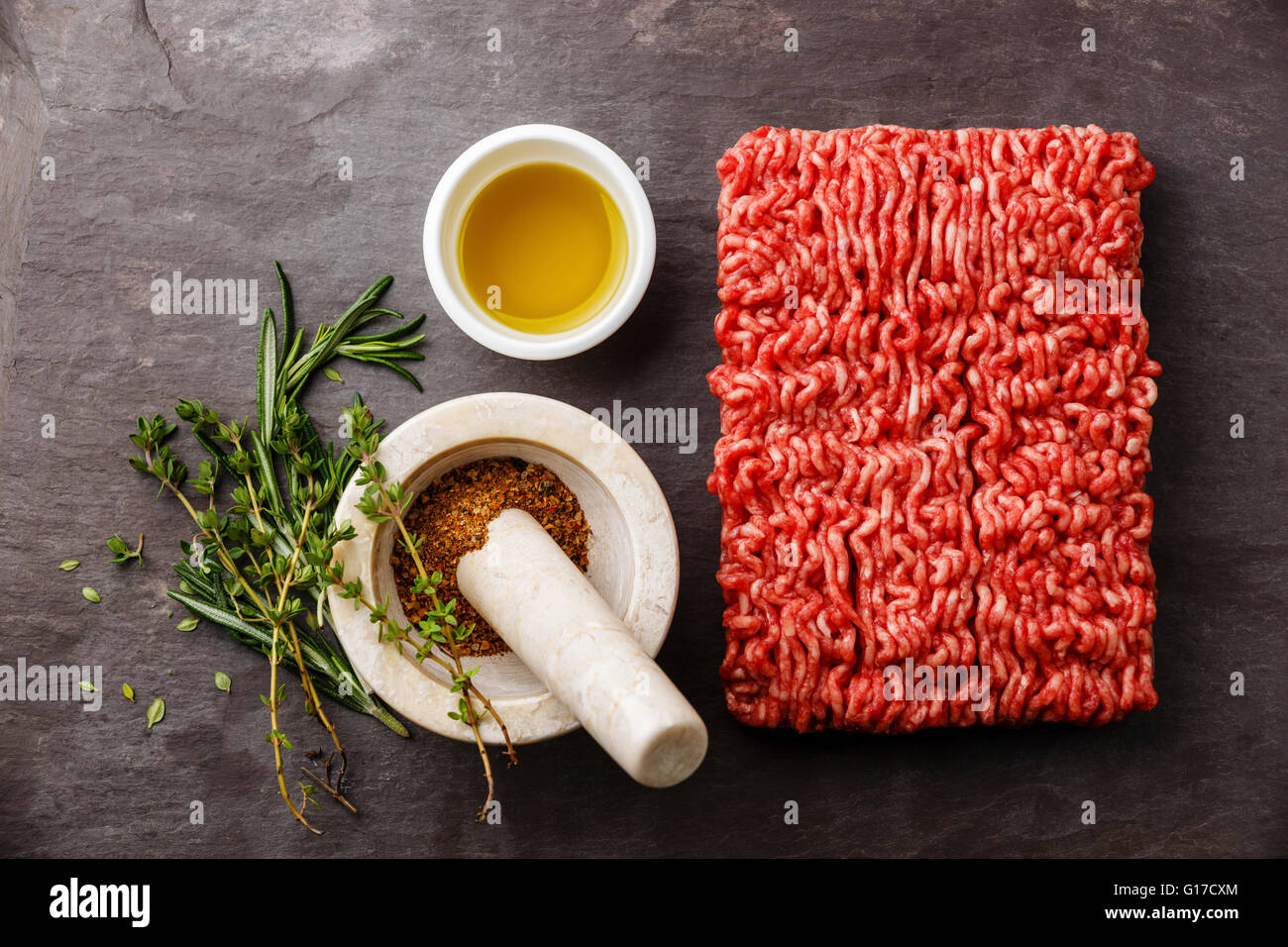 Minced meat on stone slate background with pepper, oil and herbs Stock Photo