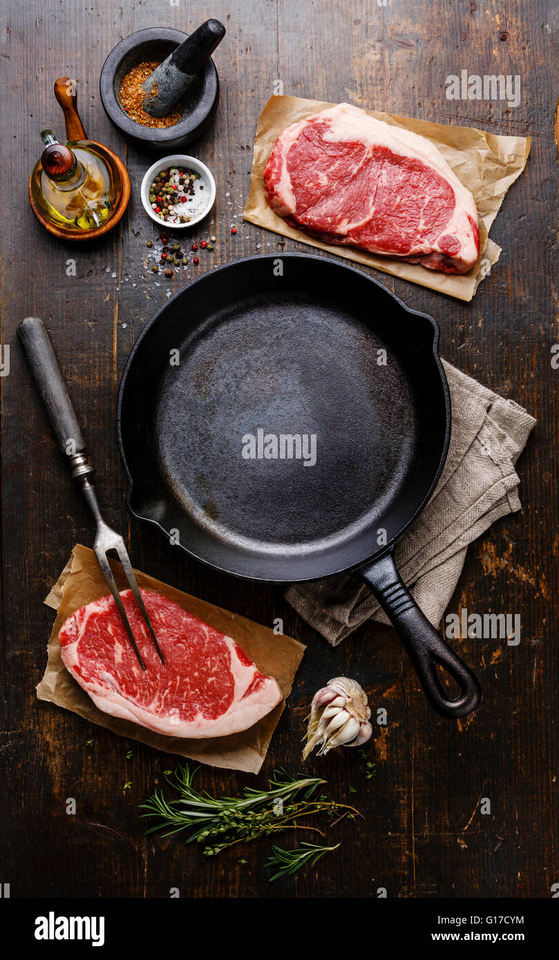 Raw fresh meat Steak Striploin for two with condiments around iron frying pan Stock Photo