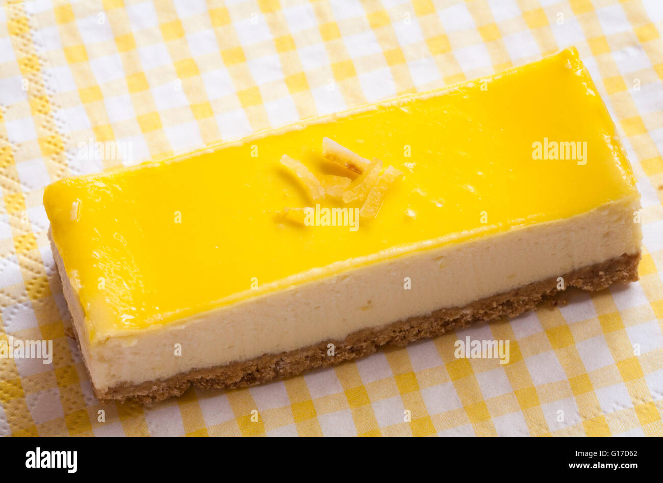 M&S Spirit of Summer lemon & ricotta cheesecake slice set on summery yellow and white checked cloth Stock Photo