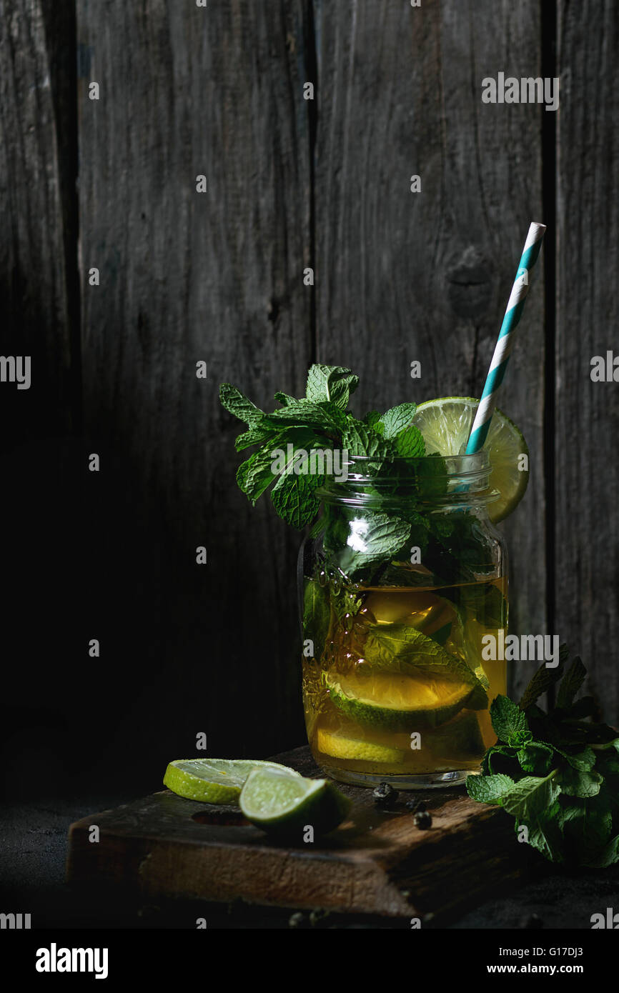 Mason jar mug with handle, lid and straw with detox cucumber agua fresca  water with lime and mint ingredients, on rustic wood kitchen table, spring  cl Stock Photo - Alamy