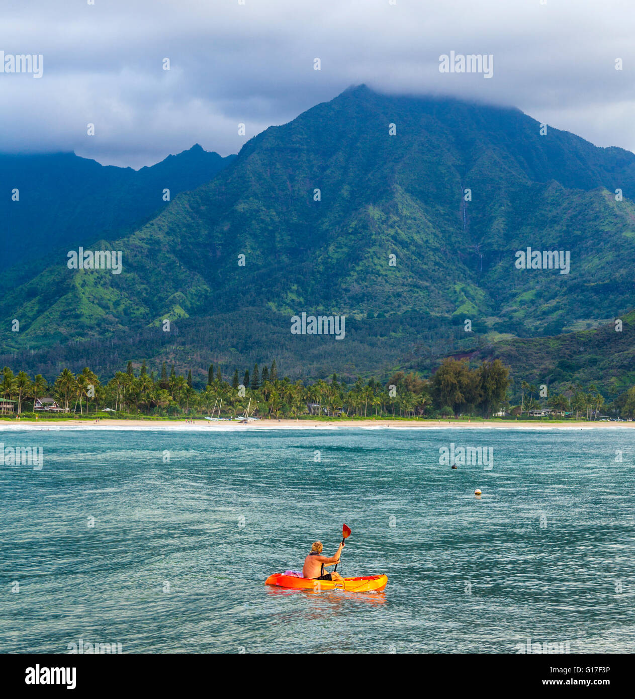 Kayaker in Hanalei Bay at sunset sees waterfall Stock Photo