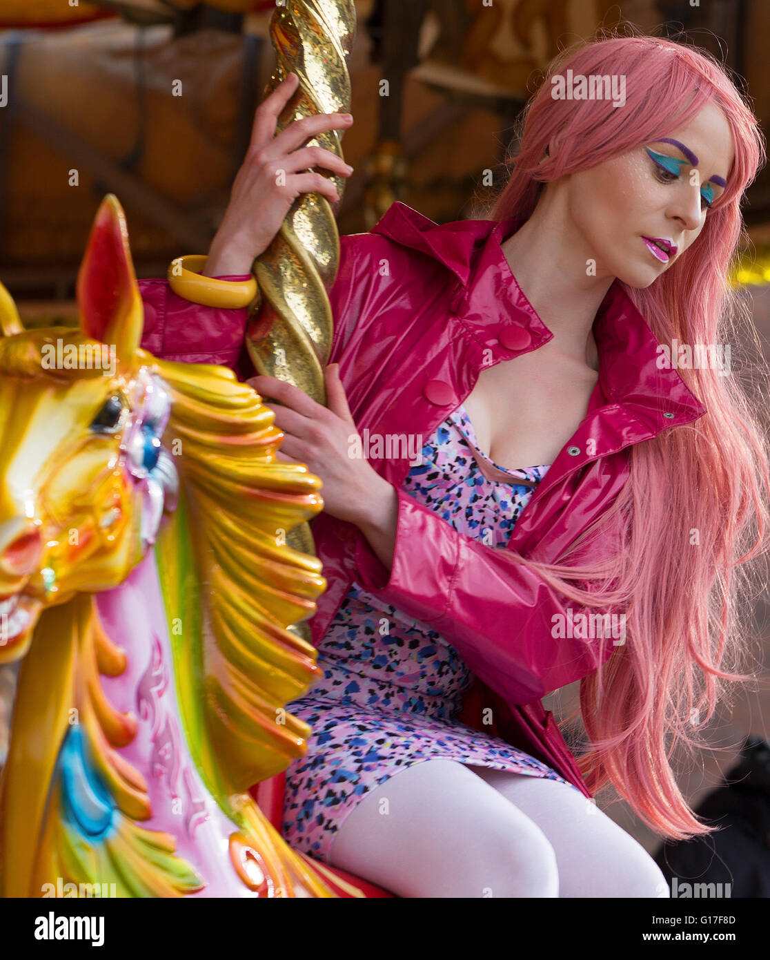 Pink hair model on merry-go-round horse Stock Photo