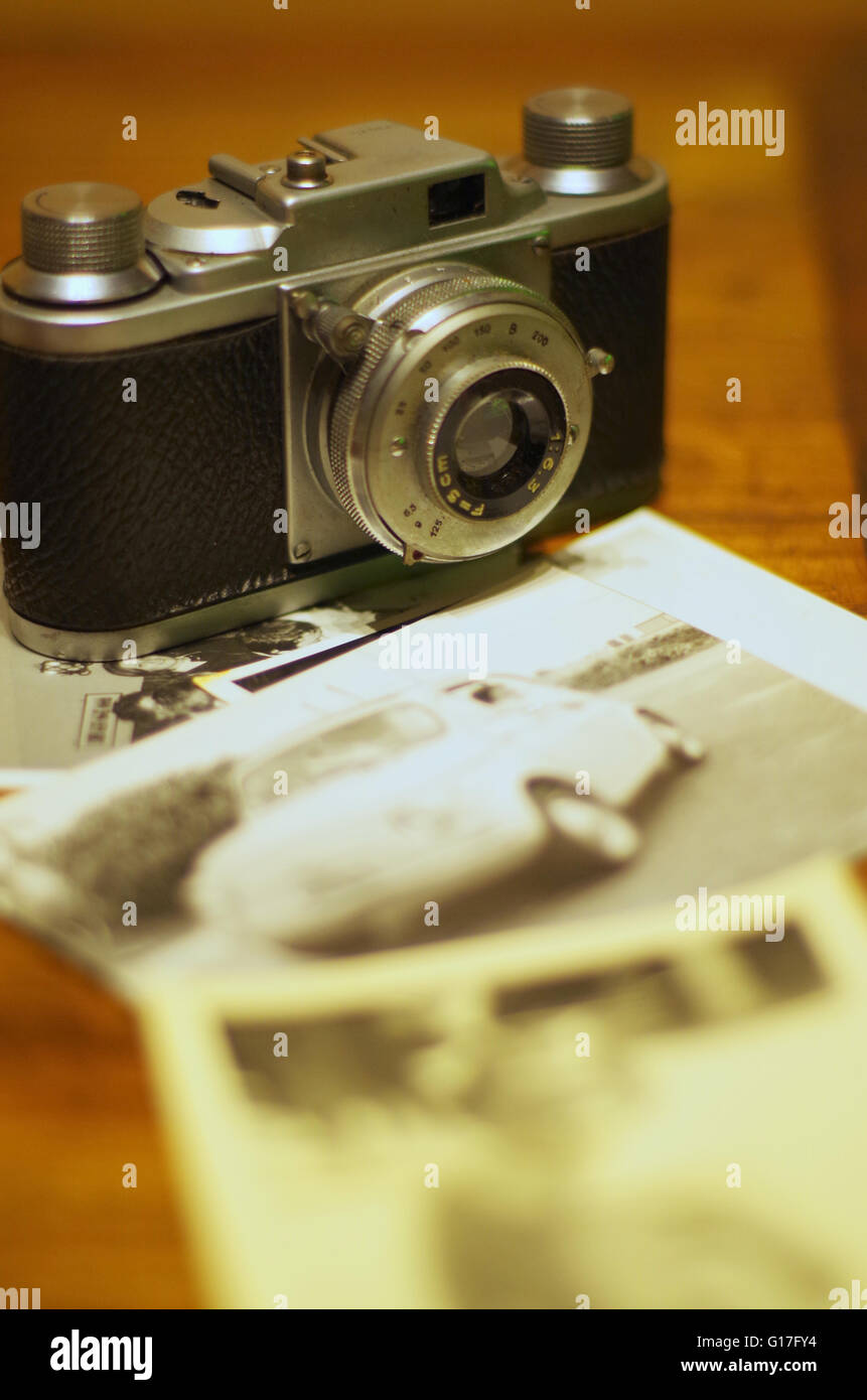 Vintage photo camera with old pictures on wooden table Stock Photo - Alamy