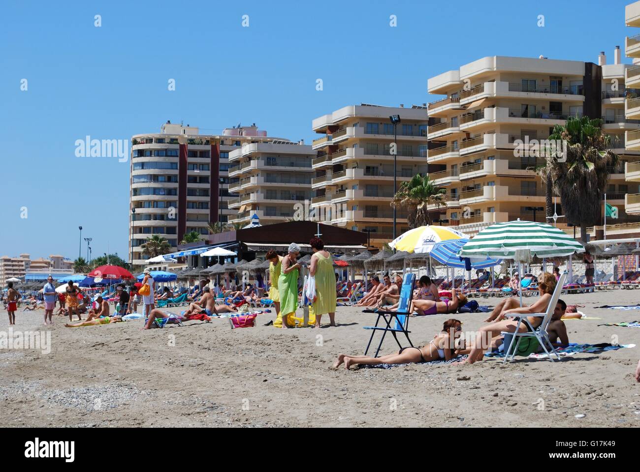 Holidaymakers relaxing on the beach with hotels and apartments to the