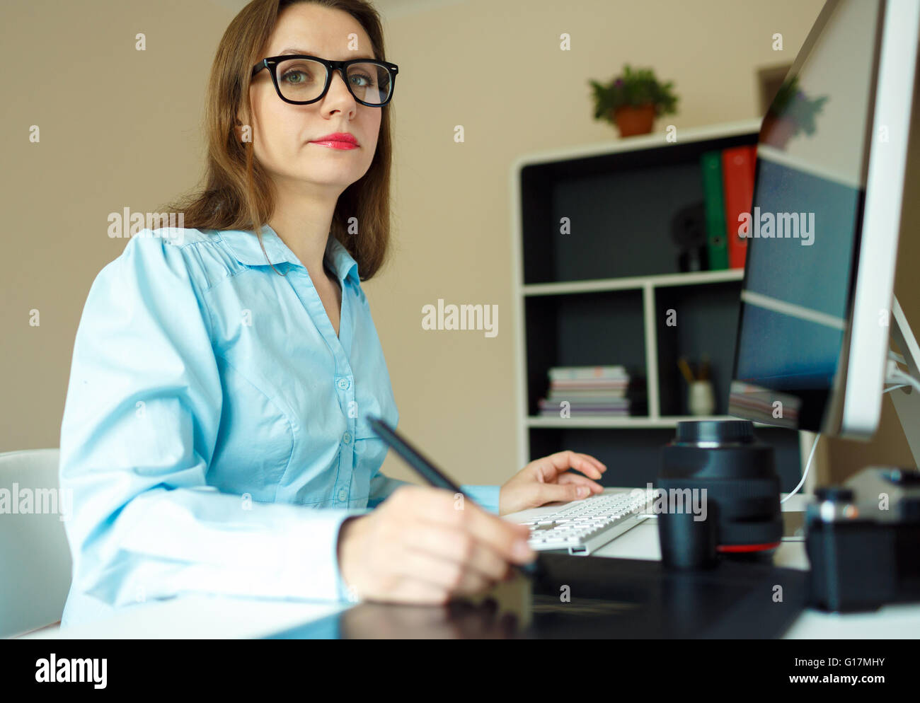 Young woman artist drawing something on graphic tablet at the home office Stock Photo