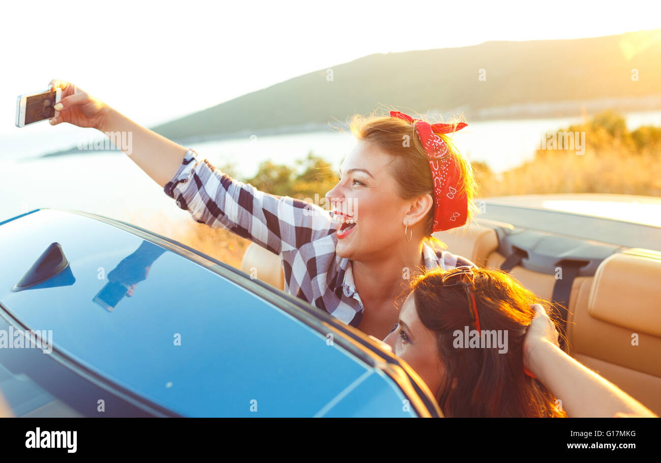 Two young beautiful girls are doing a photo of yourself in a convertible Stock Photo