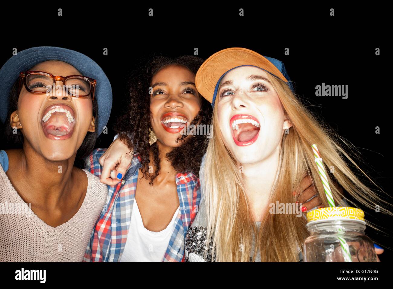 Young women huddled together looking up, mouths open smiling Stock Photo