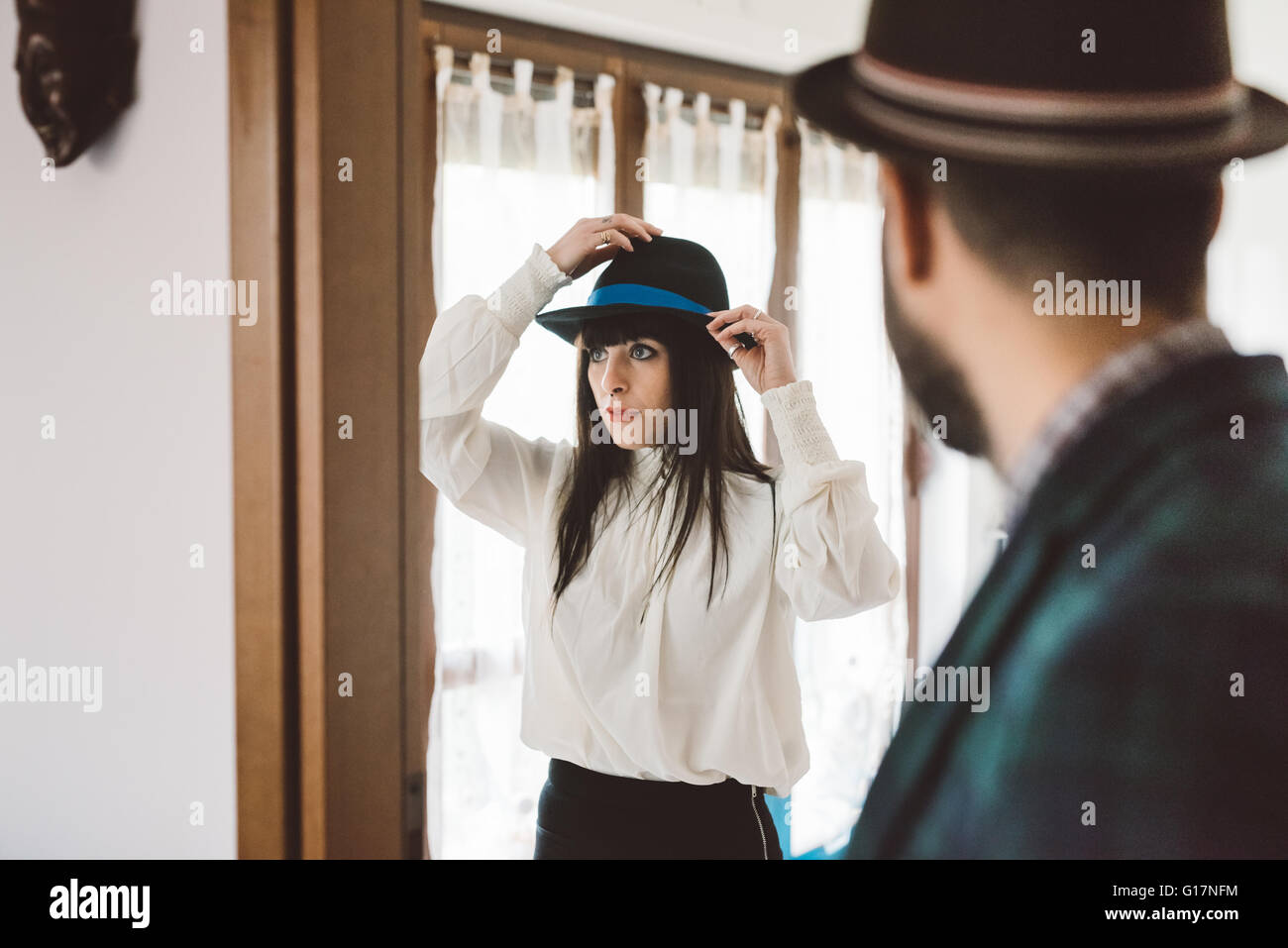 Young man waiting for woman trying on hat Stock Photo