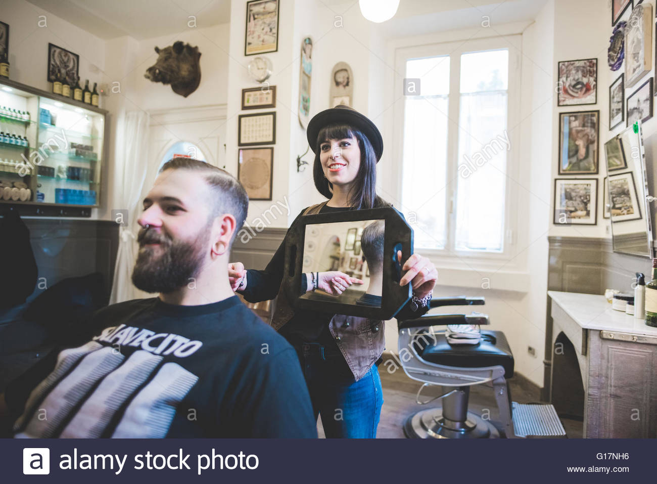 female barber holding up mirror behind man in shop stock photo female barber