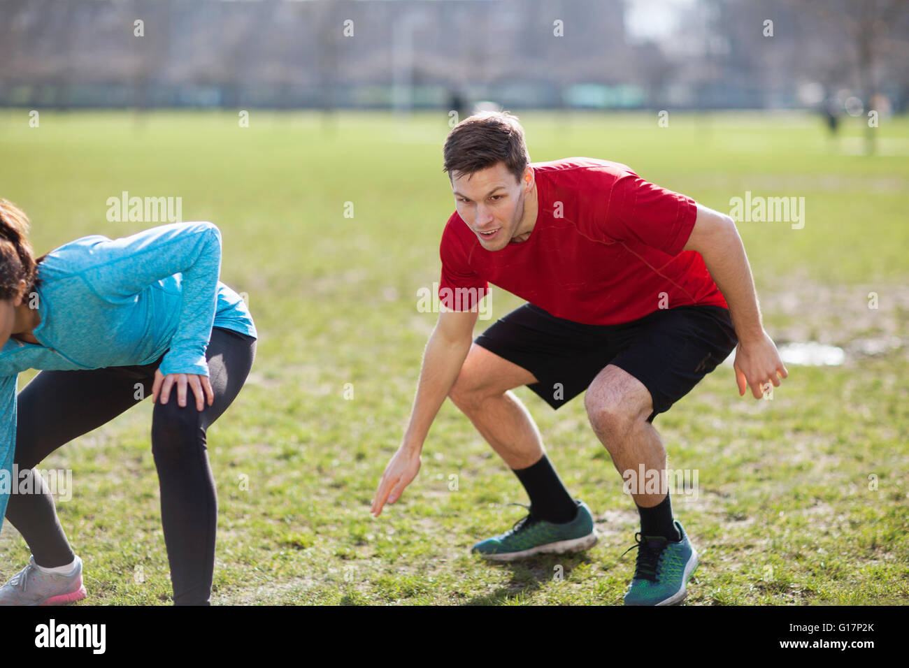 Young man and woman doing physical training on playing field Stock Photo