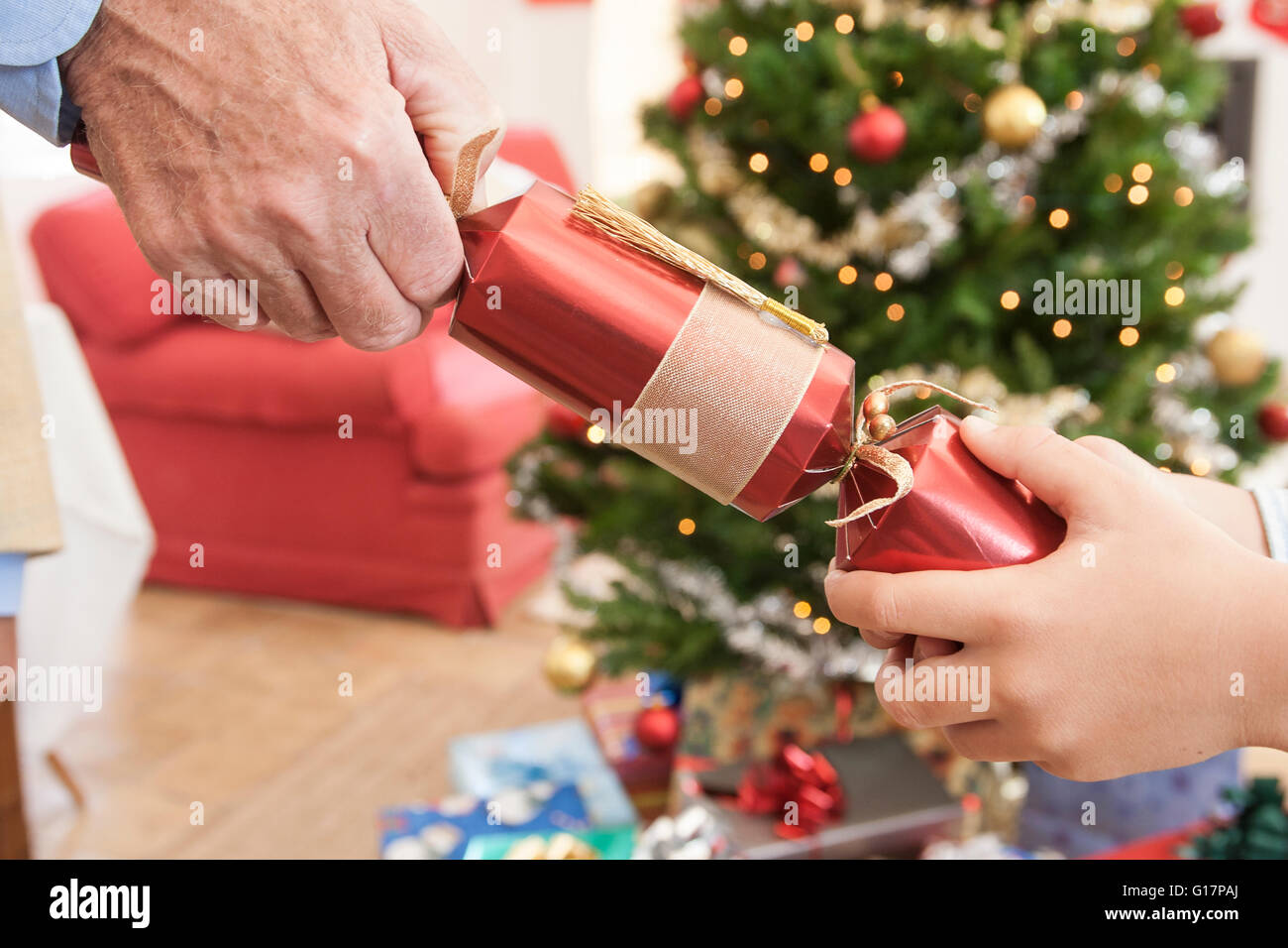 Close up of man and boys hands pulling christmas cracker Stock Photo