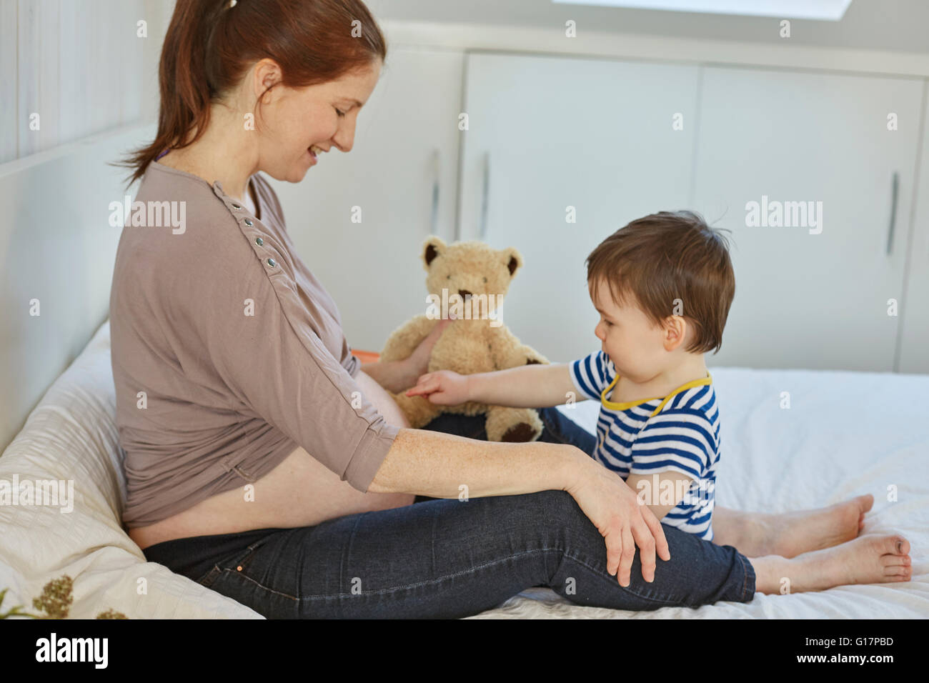 Side view of baby boy touching pregnant mothers stomach Stock Photo