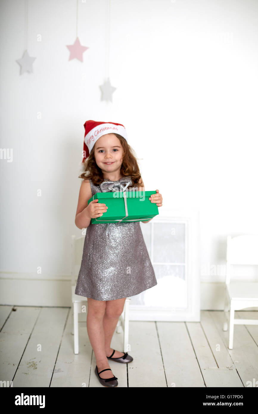 Girl in santa hat carrying Christmas gift Stock Photo