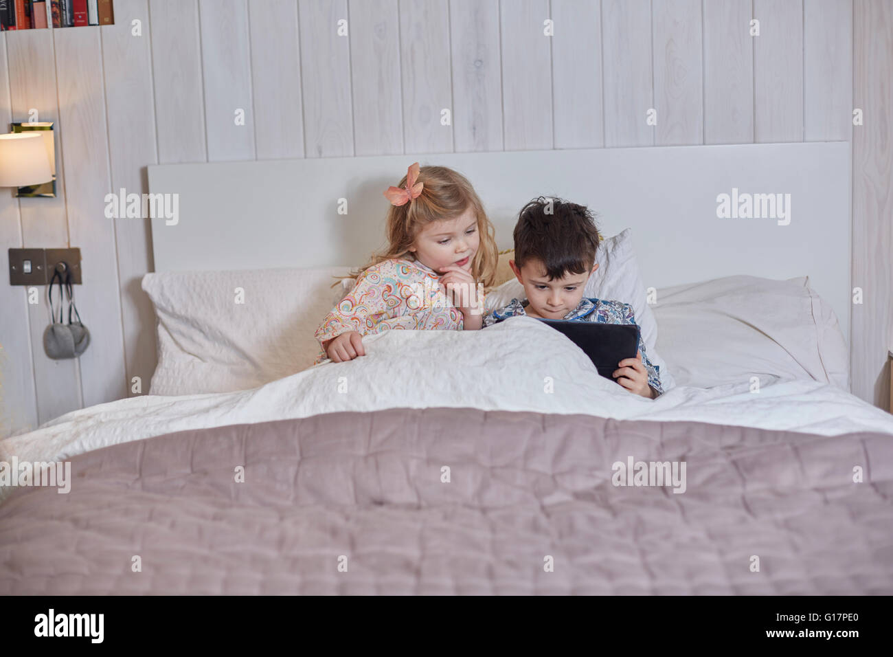 Children using digital tablet in bed Stock Photo