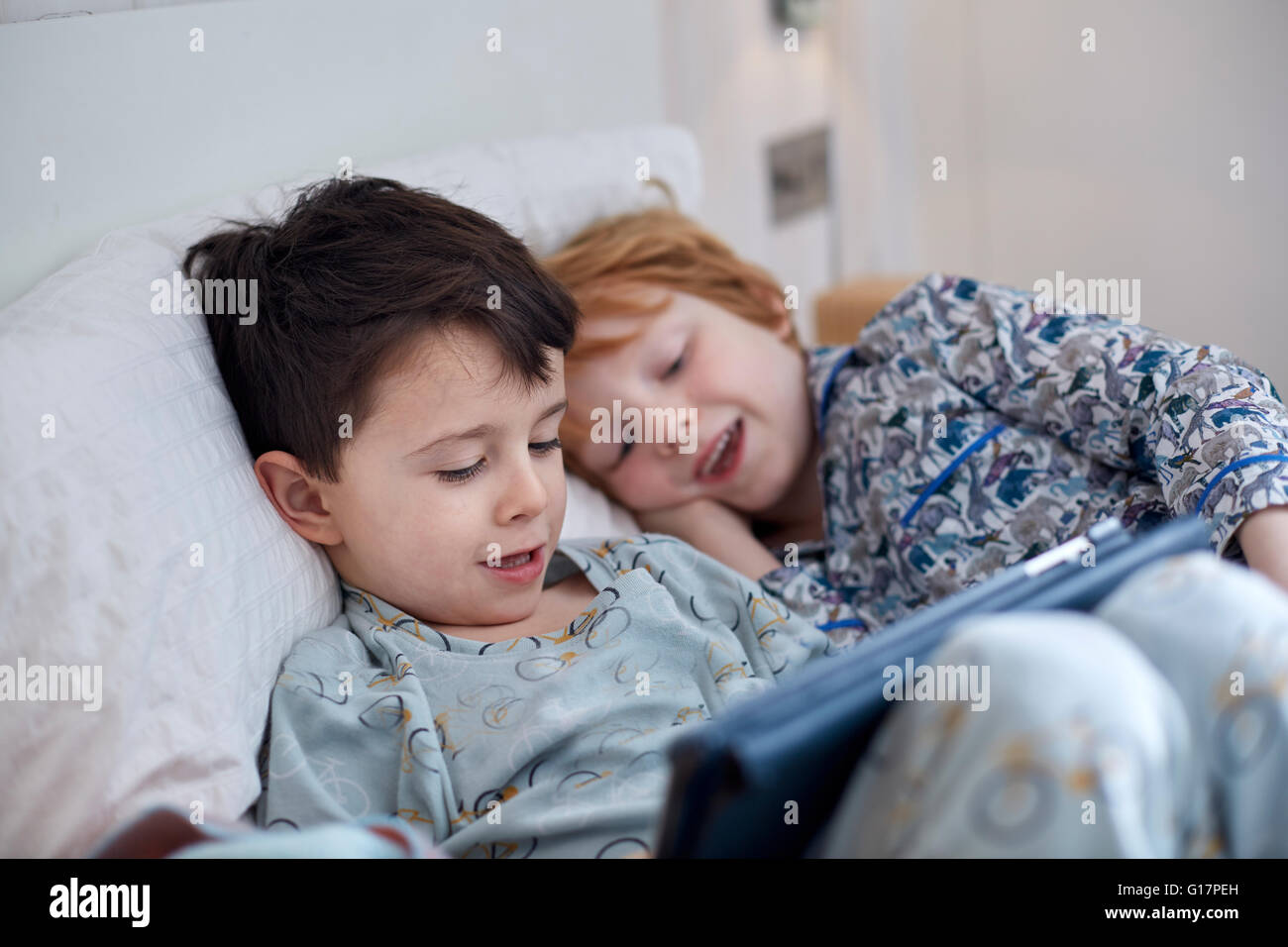 Boys in pyjamas using digital tablet in bed Stock Photo