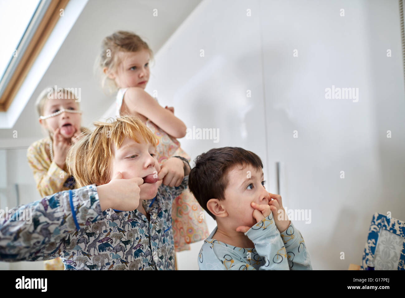 Children making faces in loft room Stock Photo