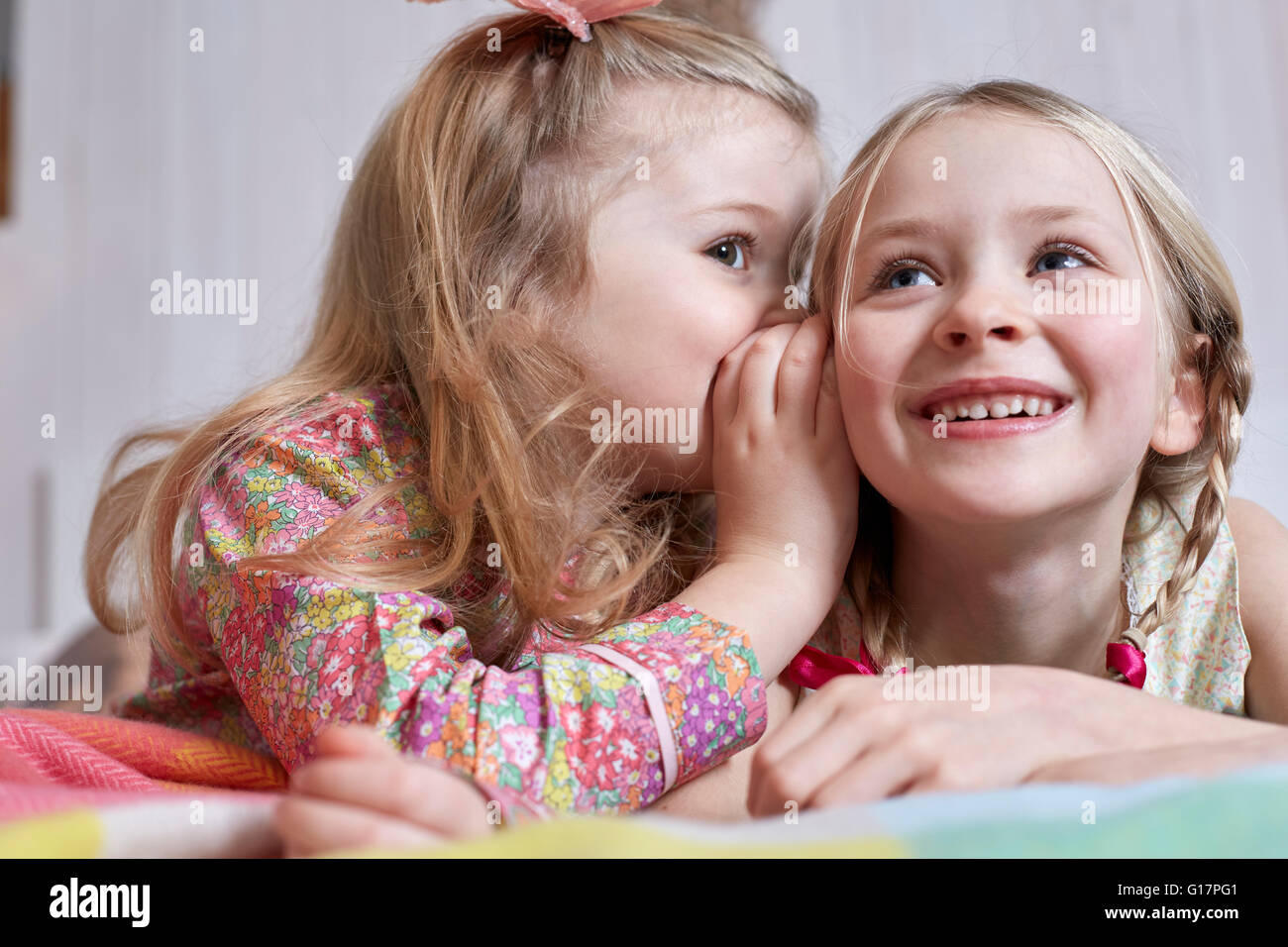 Girl whispering into sister's ear Stock Photo