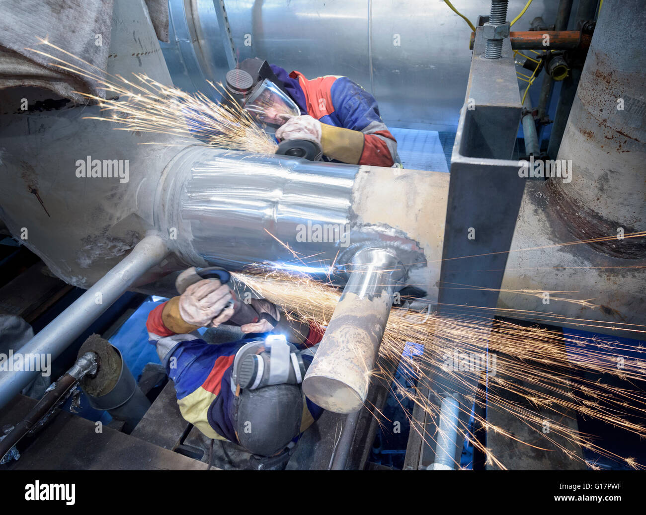 Workers grinding pipe in gas-fired power station Stock Photo