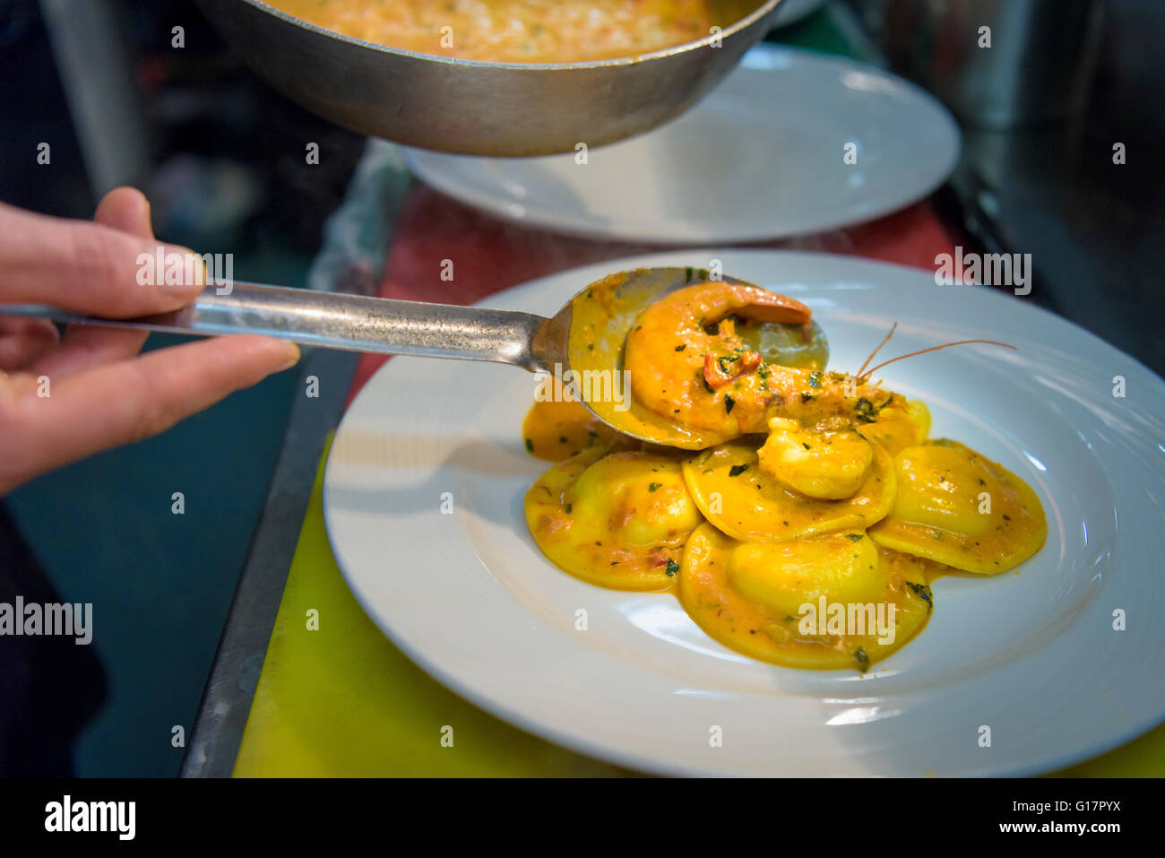 Chef plating up lobster ravioli in traditional Italian restaurant kitchen, close up Stock Photo