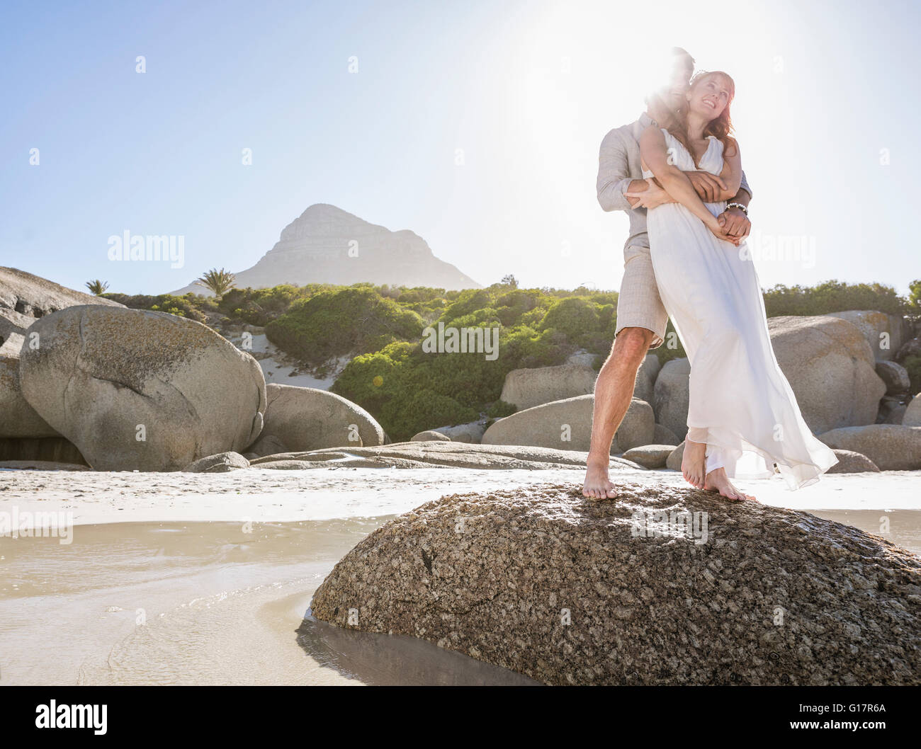 Full length view of couple standing on rocks hugging Stock Photo