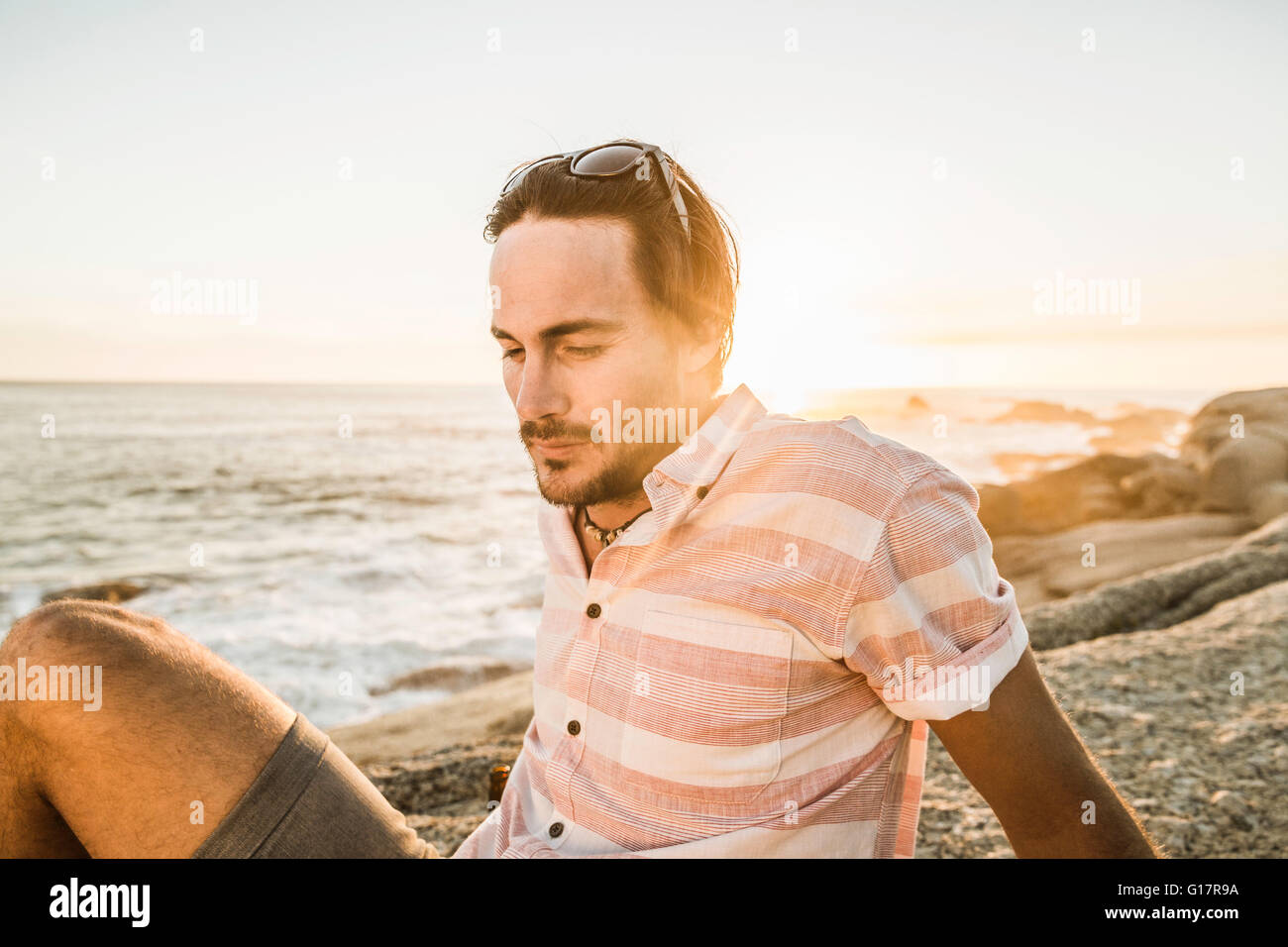 Mid adult man daydreaming on beach at sunset, Cape Town, South Africa Stock Photo