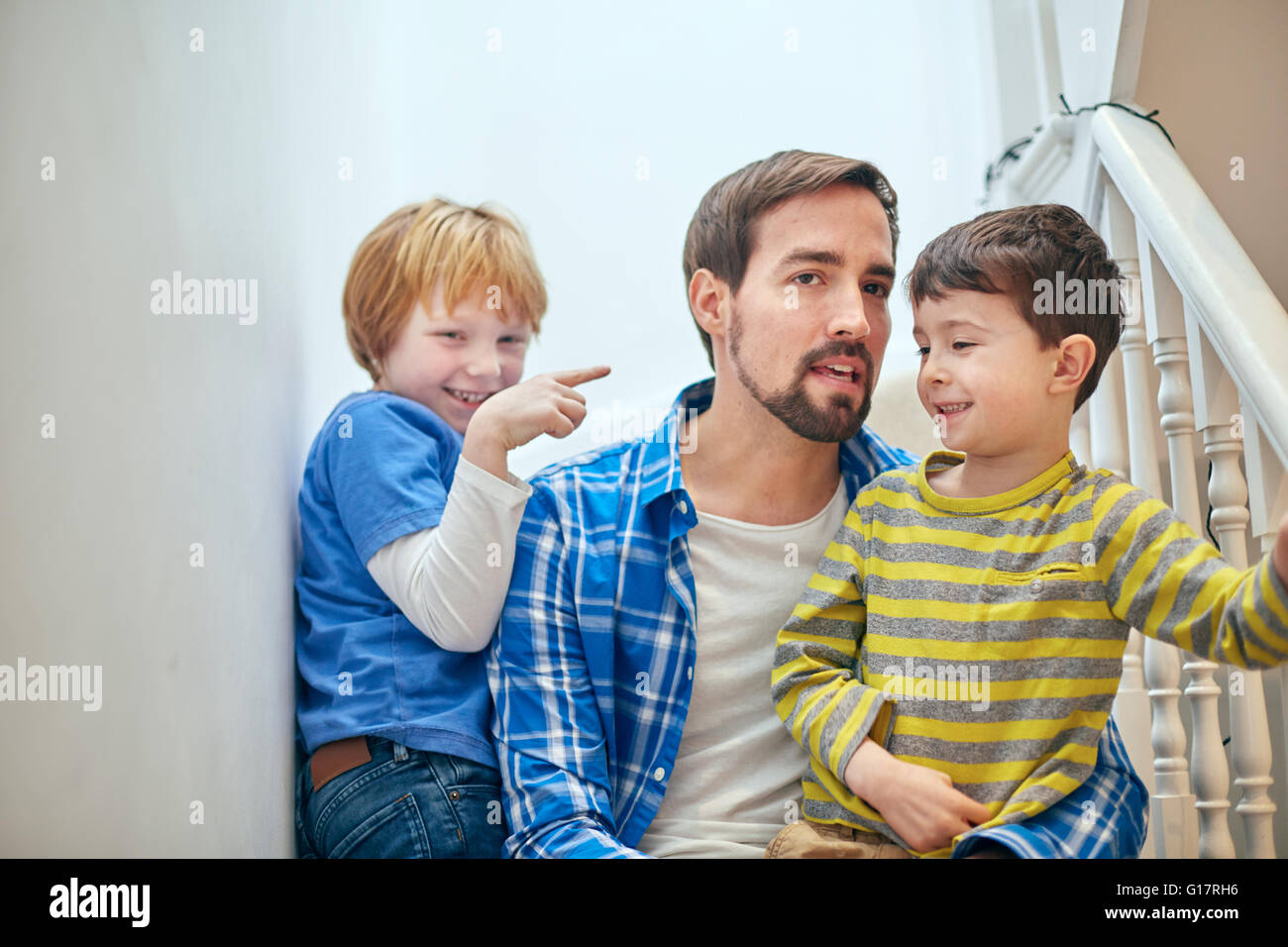 Father and sons sitting on staircase Stock Photo