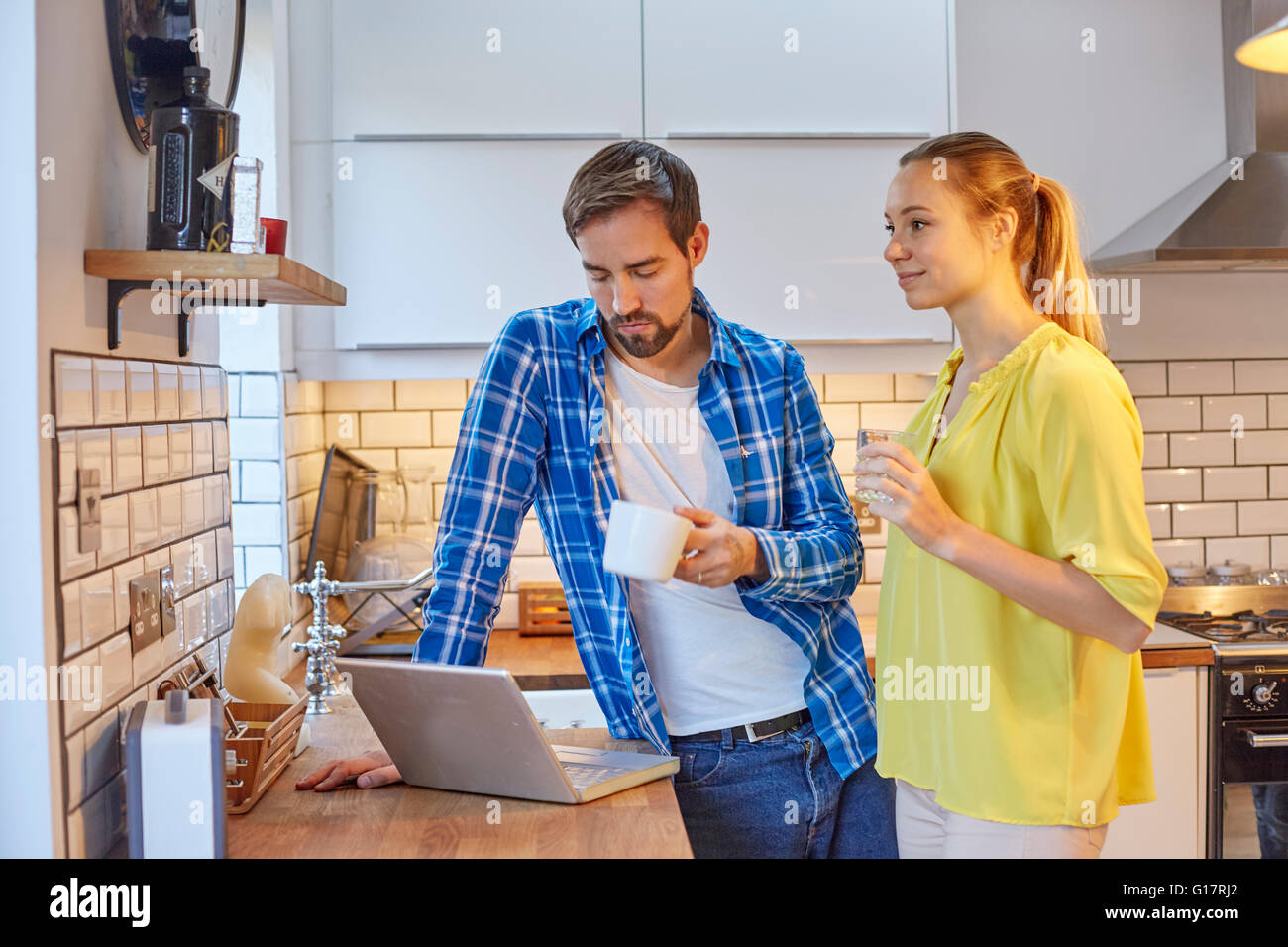 Couple using laptop and having coffee in kitchen Stock Photo